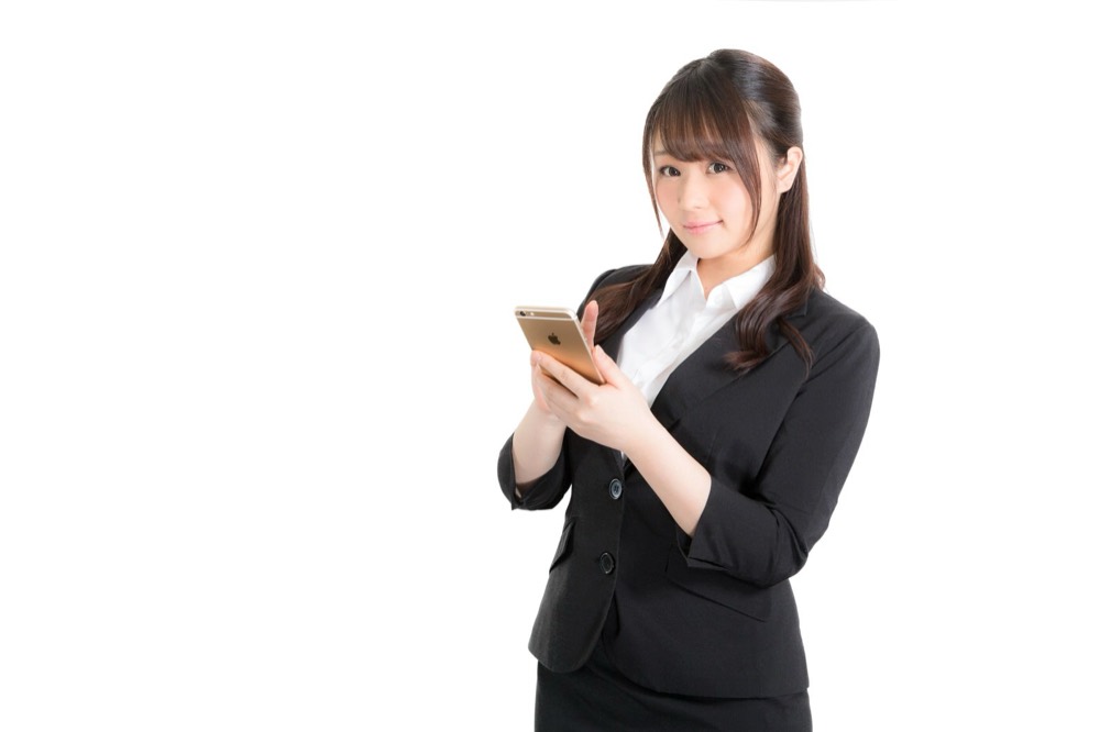 スマートフォンを操作しながら新NISAについて調べる会社員女性