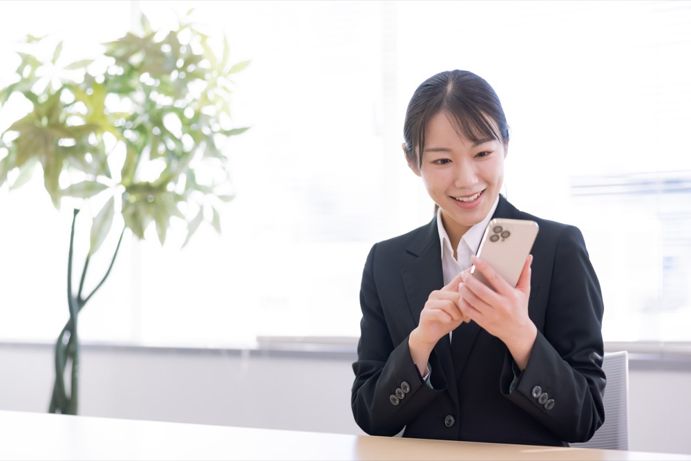 新NISAを始めて前向きな表情でスマートフォンを見る会社員女性